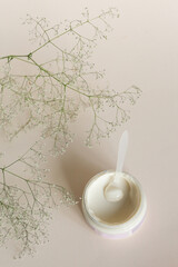 Moisturizing cosmetic cream with eucalyptus stands on neutral background with milk splash