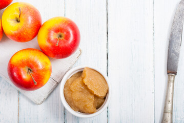 apple jam at porcelain dish, apples, cinnamon, white wood table background