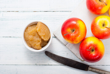 apple jam at porcelain dish, apples, cinnamon, white wood table background