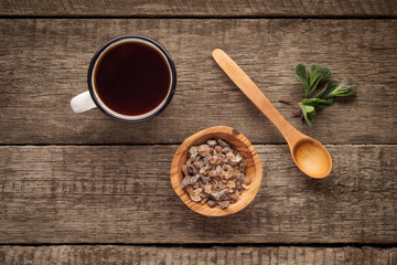 old enamel cup of tea with brown sugar mint and wooden spoon on vintage wooden background