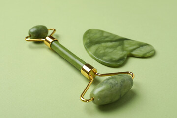 Face roller and gua sha on green background © Atlas
