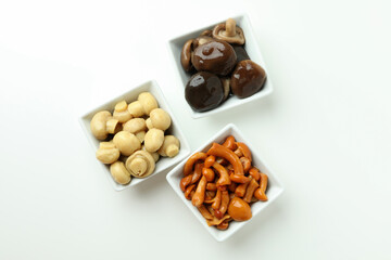 Bowls of marinated mushrooms on white background