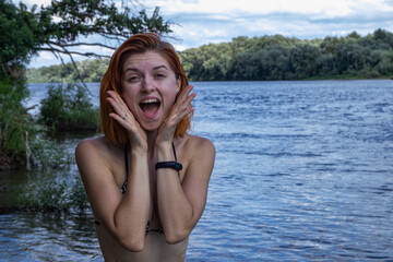 Obraz premium Beautiful girl in a swimsuit happy from the rest on the river bank 