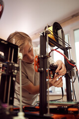 Obraz na płótnie Canvas Young male technician fixing 3D printer