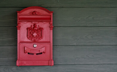Old red postbox hung on a wooden wall