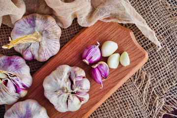 Fototapeta na wymiar Fresh head of garlic and cloves on a wooden board in a rustic style. Eco products concept
