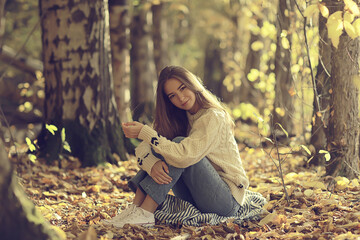 girl sitting autumn park, autumn season september in the forest - obrazy, fototapety, plakaty