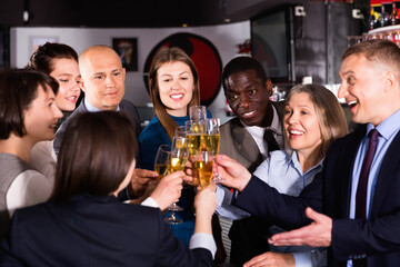 International group of glad positive businesspeople toasting with champagne, having fun at office party in nightclub
