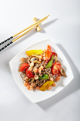 Soba noodles with seafood and vegetable. Asian style noodles food on white background. Soba in white plate with wooden choopsticks
