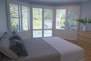 Luxury white indoor plantation shutters in bedroom - selective focus