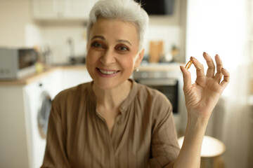 Wellness, vitamins and supplements concept. Charming grey haired senior woman wearing nice brown...