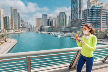 Asian woman is engaged in sports walking in the Dubai Marina area and wears a medical protective...