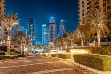 Fototapeta Paved road leading to embankment in the Dubai Marina district with numerous skyscrapers in the evening obraz