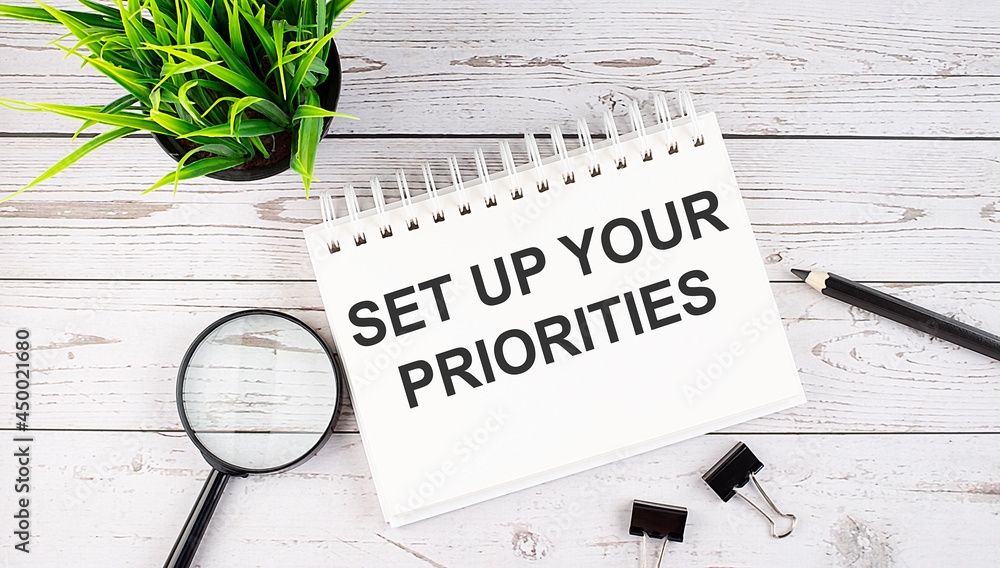 Poster set up your priorities text concept write on notebook with office tools on the wooden background