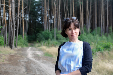 Beautiful young woman on a walk in the summer forest.