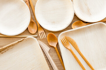 Group of dry biodegradable empty new palm leaf plates and edible fork, knife, spoon and bamboo...