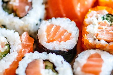 Eating various sushi. Maki, uramaki, hosomaki, sahimi and nigiri rolls set in a plate, close up composition