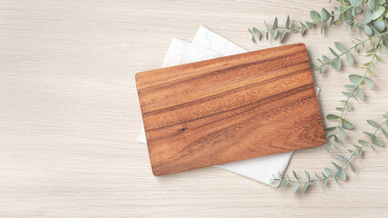 Wooded cutting board on white linen napkin with plant