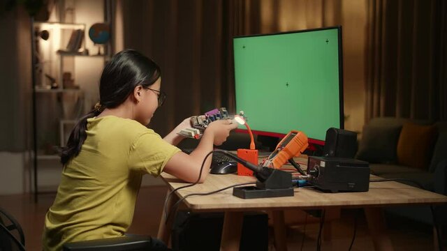 Asian Girl Is Working With Desktop Computer And Looking At Mainboard In Home, Mock Up Green Screen Display, Genius Children Concept
