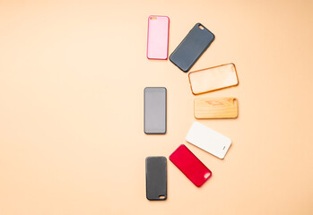 Choice of multicolored plastic back covers for mobile phones on neutral background with a smart phone on the side