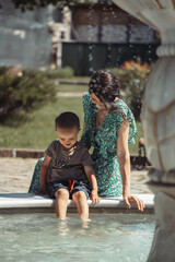 mom and son are out for a walk, mom and son are playing with water from the fountain