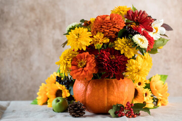 A beautiful autumn bouquet of yellow and red flowers in a pumpkin. The concept of autumn, Thanksgiving Day. Copy space.