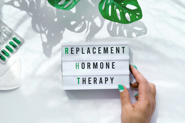 Text Replacement Hormone Therapy on light box in hand. Menopause, RHT therapy concept. Estrogen...