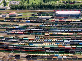 Aerial top view on railway terminal with various colorful cargo wagons. Transportation of various goods by rail. Import and export logistics. Industrial landscape. Freight sorting station.