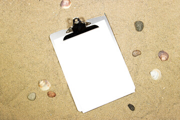 classic metal clipboard with blank white paper on sand and Sea shells, rocks. summer concept