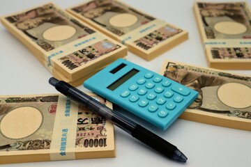 日本の紙幣と電卓とボールペン