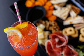 Aperitivo da bar con cocktail, taralli, salatini, noci, formaggio, prosciutto crudo mini tramezzini e salsa barbecue