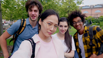 Group of multi-ethnic teen friends taking selfie outdoors and smiling at camera