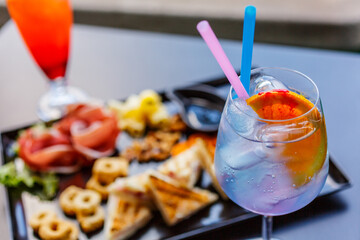 Aperitivo da bar con cocktail, taralli, salatini, noci, formaggio, prosciutto crudo mini tramezzini e salsa barbecue