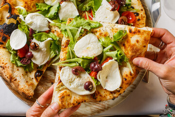 Pizza napoletana con mozzarella di bufala fresca, pomodori, rucola, basilico e olive