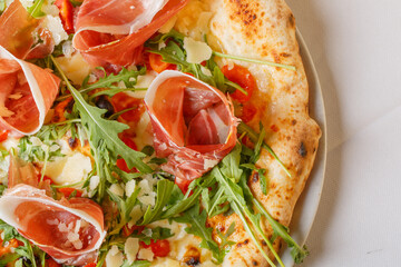 Pizza napoletana con rucola, prosciutto crudo, pomodori e mozzarella di bufala
