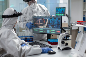 Medical specialist team wearing protective equipment against covid19 looking at coronavirus vaccine expertise on computer during virus examination in hospital laboratory. Clinical experiment