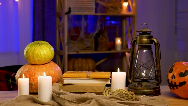 Decorated room with pumpkins with scary faces, burning candles, oil lamp, cobwebs. Traditional symbol of Halloween. Zoom in in slow motion. The background is blurred. Close up.