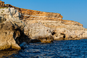 Fototapeta na wymiar Black Sea orange rocks coastline. Coastal orage rocks and blue sea. Landscape Summer. Traveling. Sevastopol, Crimea, Russia.