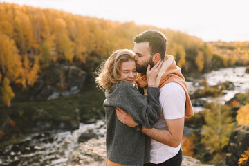 A happy couple in love in casual clothes travel together, hike and have fun in the autumn forest, enjoy nature on a weekend in fall. A man and a woman on a romantic date countryside