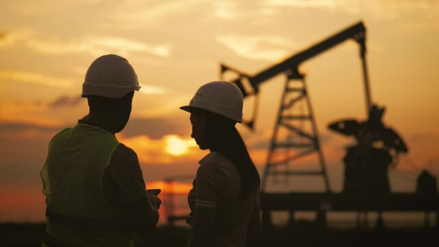 Industrial, oil and teamwork. A team engineers discussing the maintenance of a oil pump field. Engineering team working in Oil refinery. Silhouette working engineers oil rig.