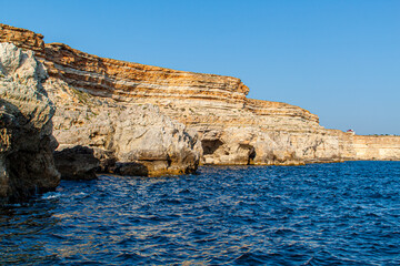 Fototapeta na wymiar Black Sea orange rocks coastline. Coastal orage rocks and blue sea. Landscape Summer. Traveling. Sevastopol, Crimea, Russia.