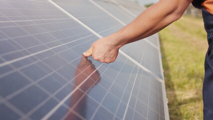 Close up of a young engineer hand is checking the operation of sun and cleanliness of photovoltaic...