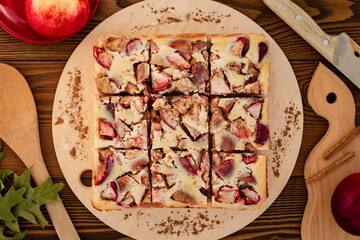 top view of apple pie with creamy filling cutting into squares, autumn menu flat lay on wooden...