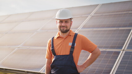 Portrait of confident engineer of solar cell farm industry. Staff confident pose Solar cell panel installation. Close up portrait of male worker in protective helmet standing near solar panel