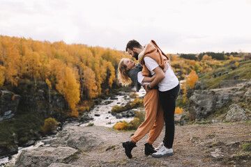 A happy couple in love in casual clothes travel together, hike and have fun in the autumn forest, enjoy nature on a weekend in fall. A man and a woman on a romantic date countryside