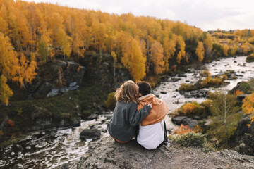 A happy couple in love in casual clothes travel together, hike and have fun in the autumn forest,...