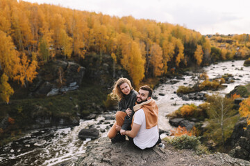 Naklejka na ściany i meble A happy couple in love in casual clothes travel together, hike and have fun in the autumn forest, enjoy nature on a weekend in fall. A man and a woman on a romantic date countryside
