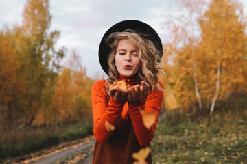 A happy pretty smiling young woman in casual warm clothes enjoys solitude drinking coffee walking traveling by car in the autumn forest in nature golden fall