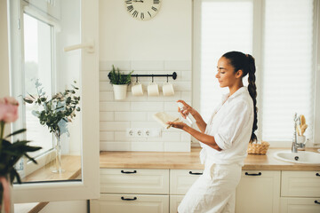 Young woman cleaning house using spray and natural rag standing in a kitchen.