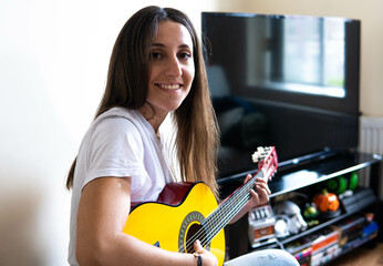Fototapeta na wymiar Music Concepts. Latin girl playing guitar. Latin girl relaxing with music. Latin woman have a happy lifestyle. Beautiful Latin girl playing guitar at home. 